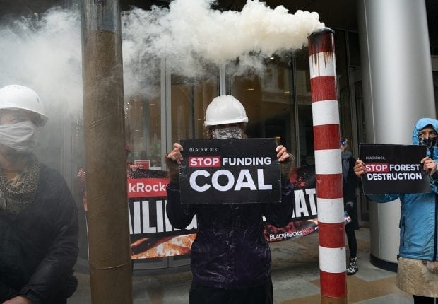 Activist carrying sign that reads "BlackRock stop funding coal".